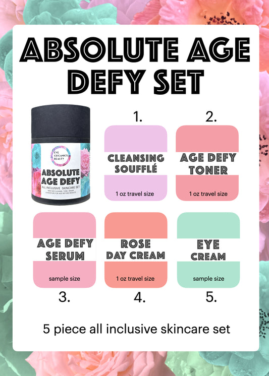 A 5-piece trial moisturizer sampler set from Absolute Age Defy, featuring a black jar of Cleansing Soufflé alongside five color-coded travel-size swatches for Age Defy Toner, Age Defy Serum, Rose Day Cream, Eye Cream, and another pink item, all arranged on a white card with a pink floral background.